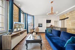 La Suite Indivio - Appartement standing vue cathédrale في ديجون: غرفة معيشة مع أريكة زرقاء ومطبخ
