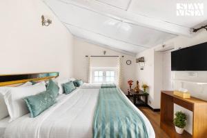 a bedroom with a large white bed with blue pillows at StayVista at The Alcove with Breakfast & BBQ Grill in Ooty