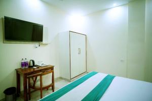 1 dormitorio con 1 cama, escritorio y TV en icyhotels ADA residency and confrence centre, en Noida