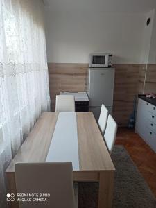 a dining room table with chairs and a microwave at Apartman NINA in Kuršumlija