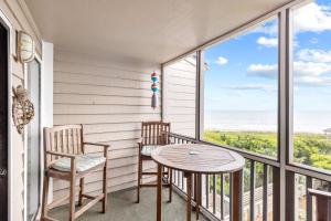 uma varanda com 2 cadeiras, uma mesa e uma mesa em Island Time condo em Atlantic Beach