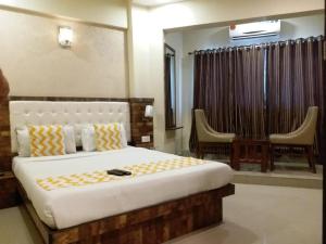 a bedroom with a large bed and two chairs at Hotel Golden Park Near NESCO in Mumbai