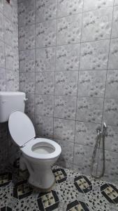 a bathroom with a toilet and a tiled wall at Santai Desa Chalet musleem 0nly in Brinchang