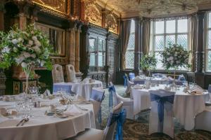 una habitación con mesas blancas y sillas con flores en Crewe Hall Hotel & Spa - Cheshire, en Crewe