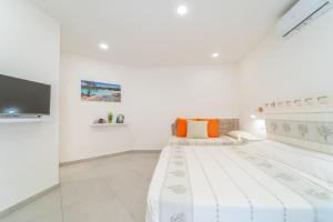 een witte slaapkamer met 2 bedden en een flatscreen-tv bij Brorent Affittacamere moro dream rooms in Olbia