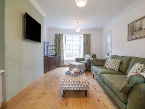 a living room with a green couch and a table at 23 Church Farm Lane in Halesworth