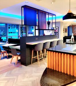 a kitchen with a bar with chairs and tables at Holiday Inn Birmingham North - Cannock, an IHG Hotel in Cannock