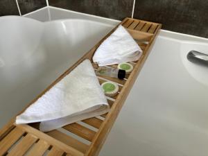 a bath tub with a wooden tray next to a sink at Luxury Furnished 2 Bed Northampton apartment with Balcony near NN5 stadium in Northampton