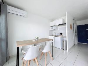 a kitchen with a wooden table and white chairs at 3319-appartement à 200m de la plage in Le Barcarès