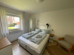 a bedroom with a bed and a chair and a window at Apartment am Stadtgarten in Norden