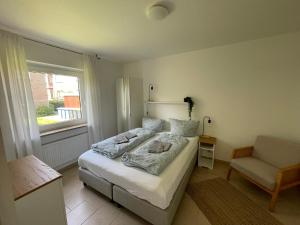 a bedroom with a bed and a chair and a window at Apartment am Stadtgarten in Norden