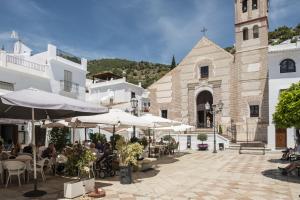 a group of people sitting at tables in front of a church at Plaza Iglesia in Frigiliana
