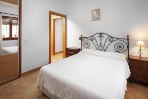 a bedroom with a white bed and a mirror at Plaza Iglesia in Frigiliana