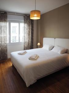 um quarto com uma grande cama branca com duas toalhas em Les Pingouins de la Gare em Brest