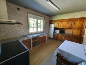 a kitchen with wooden cabinets and a black refrigerator at Prado verde in Santa Comba