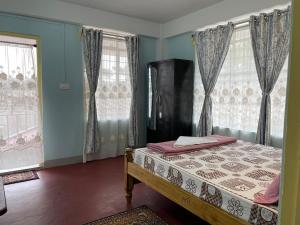 a bedroom with a bed and two windows at Keeon Private Room Top in Shillong