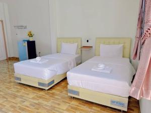twee bedden naast elkaar in een kamer bij โรงแรม ปาล์มเพลส in Ban Wang Phai Tha Kham