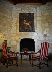 a stone fireplace with two chairs and a table at Chateau de la Vieille Chapelle in Lugon et l’Ile du Carney