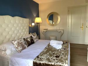 una camera da letto con un letto bianco con una grande testiera e uno specchio di Hotel Ca' D'Oro a Bibione