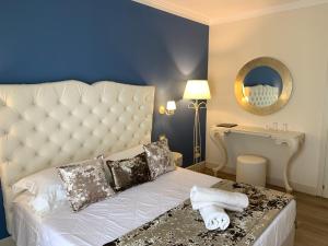 una camera da letto con un grande letto bianco con una parete blu di Hotel Ca' D'Oro a Bibione