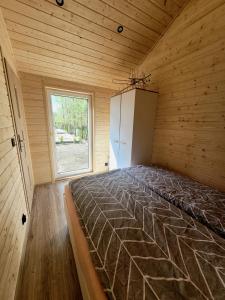 a large bed in a wooden room with a window at Domki Wakacyjne "Morskie Wrota"Karwieńskie Błota in Karwieńskie Błoto Drugie