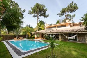 a house with a swimming pool in front of a yard at Oasis Piscine et Golf 4ch Caparica in Aroeira
