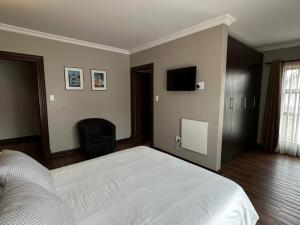 a bedroom with a bed and a flat screen tv at Cozy In Jozi in Edenvale