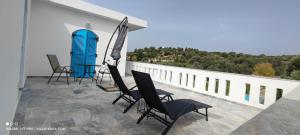 eine Gruppe von Stühlen und einem Sonnenschirm auf dem Balkon in der Unterkunft VILLA KARA - Bed and Breakfast in Mési