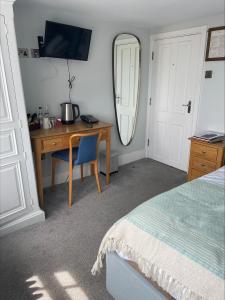 um quarto com uma secretária, uma cama e um espelho em The Royal Albion em Broadstairs