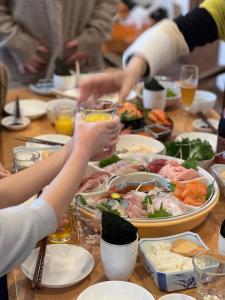 um grupo de pessoas sentadas à volta de uma mesa com comida em Populasunupuri - Vacation STAY 62945v em Otaru