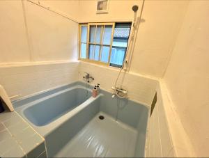 湯河原的住宿－温泉街の入り口にあるゲストハウス SLOW HOUSE yugawara，带窗户的浴室内的蓝色浴缸