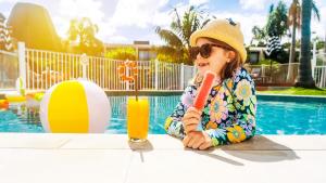 a little girl sitting at a table with a drink at Holiday Inn Auckland Airport by IHG in Auckland