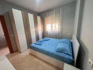 une petite chambre avec un lit avec des draps bleus dans l'établissement Adrian’s apartment, à Orikum