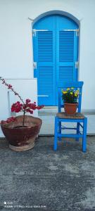 Mési的住宿－VILLA KARA - Bed and Breakfast，蓝色椅子和蓝色门旁边的盆栽植物