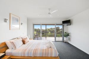 a white bedroom with a bed and a tv at Saltwater Breeze Retreat in Cowes