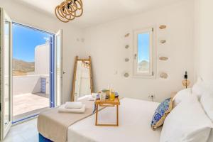 a white room with a bed and a table at Paros Sea View Eco - Aetherian Ciel Villas, Aktaia in Mármara
