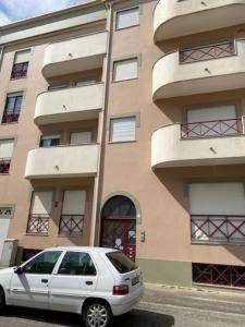 una macchina bianca parcheggiata di fronte a un edificio di SwordFish Beach Apartment a Peniche