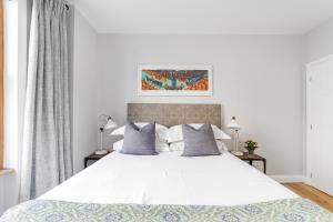 1 dormitorio con 1 cama blanca grande con almohadas grises en Munster Village in Fulham, en Londres