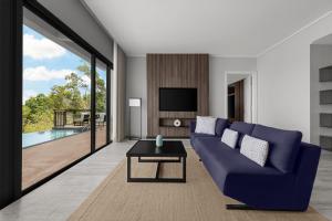 Perhentian Marriott Resort & Spa في بيرهينتيان: غرفة معيشة مع أريكة زرقاء وتلفزيون