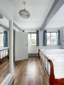 Schlafzimmer mit einem Bett, einer Tür und Fenstern in der Unterkunft Pension Sandbogaard in Sandvig