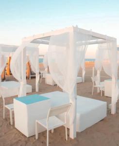 Tienda blanca y sillas en la playa en Hotel Etna, en Riccione