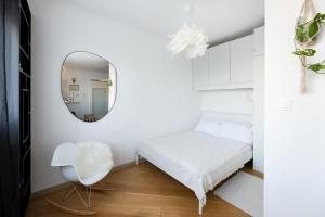 a white bedroom with a mirror and a white chair at cozinesT eco apartment in Zagreb