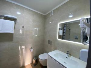 W łazience znajduje się umywalka, toaleta i lustro. w obiekcie Skif HOTEL & SPA w mieście Pietropawłowsk Kamczacki