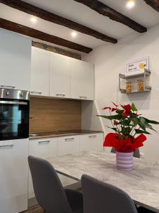 a kitchen with white cabinets and a table with a vase of flowers at Casa Salvia in Koper