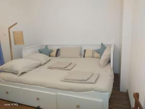 a white bed with blue pillows on it at Jolie maison paisible, avec jardinet et parking in Gujan-Mestras