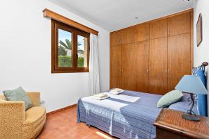 ein Schlafzimmer mit einem Bett, einem Stuhl und einem Fenster in der Unterkunft Villa Angel in Son Xoriguer