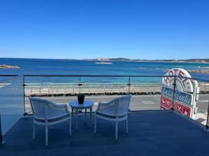 einen Tisch und Stühle auf einem Balkon mit Meerblick in der Unterkunft Hotel La Lanzada in A Lanzada