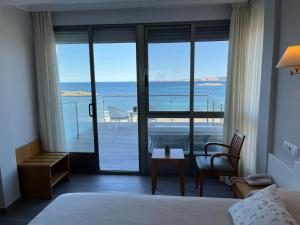a bedroom with a bed and a view of the ocean at Hotel La Lanzada in A Lanzada