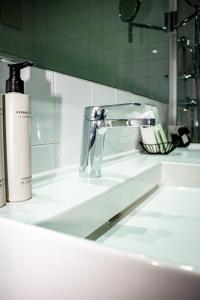 um lavatório de casa de banho com uma torneira e um espelho em Augarten Art Hotel, a Member of Design Hotels em Graz