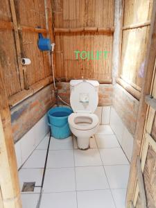 a bathroom with a toilet and a blue bucket at Tado Homestay in Limbung